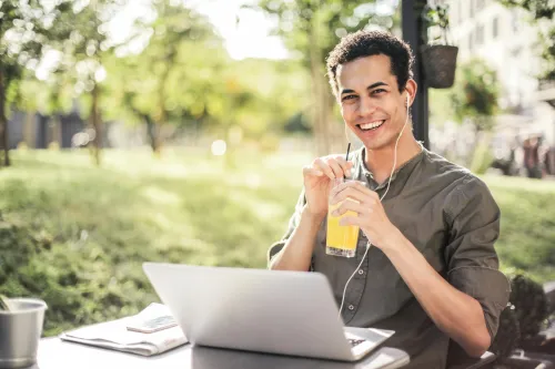 Mann mit Laptop und Papiernoten im Hintergrund