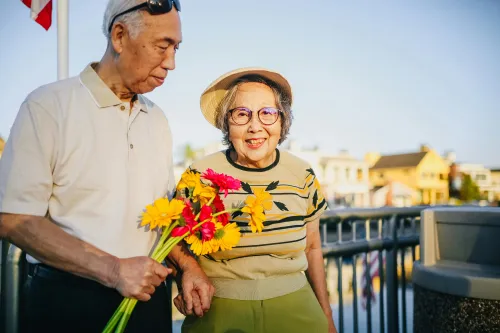 Frau mittleren Alters mit Blumen bei einem älteren Mann