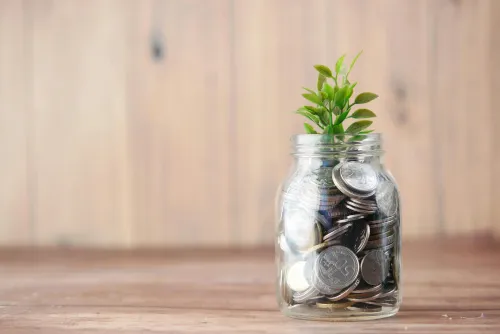 Münzen in einem Glas als Symbol für Investitionen und Ersparnisse